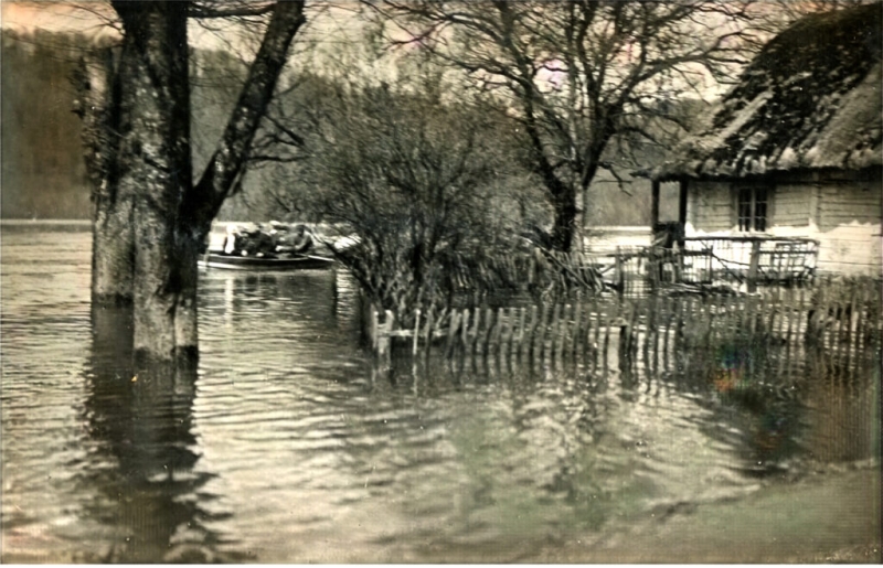 Plūdi Gaujā, applūdusi arī pārcēlāja māja. Gaujas straumē laiviņa ar otrā krastā tikt gribētājiem (tālāk aiz kokiem). Fotopastkarte 20. gs. 20. &nbsp;gadi. Foto: O. Lessiņš