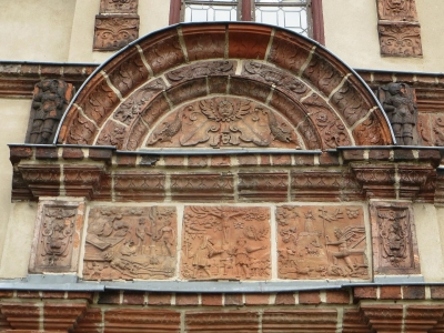 Tuvplāns uz Gādebušas pils portālu Vācijā; greznais renesanses stila dekors ietver terakotas ciļņus ar figūrām un ornamentiem, kas izvietoti virs ieejas arkas.