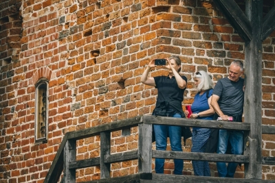 apmeklētāji uz pils koka galerijas fona.