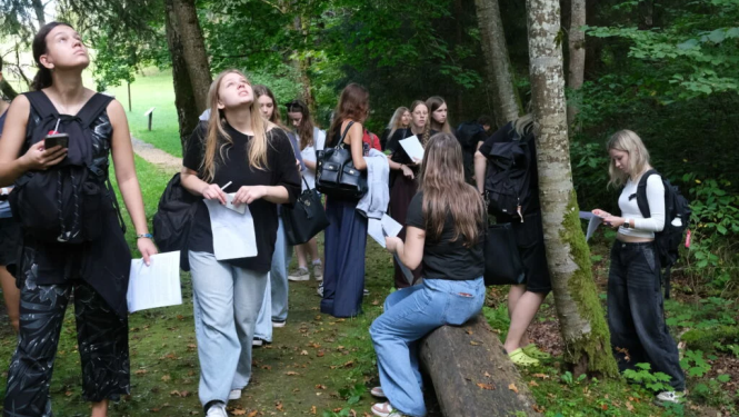 Koksnes krājas salīdzināšana kokiem Turaidas muzejrezervāta meža parkā 7.–9. klašu skolēniem. Skolnieku grupa pēta kokus.