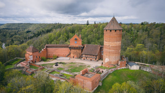 Turaidas pils skats no putna lidojuma un paziņojums par jaunu maksas pakalpojumu cenrādi muzejrezervātā.