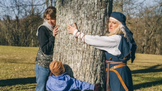 Women and two children hugging tree