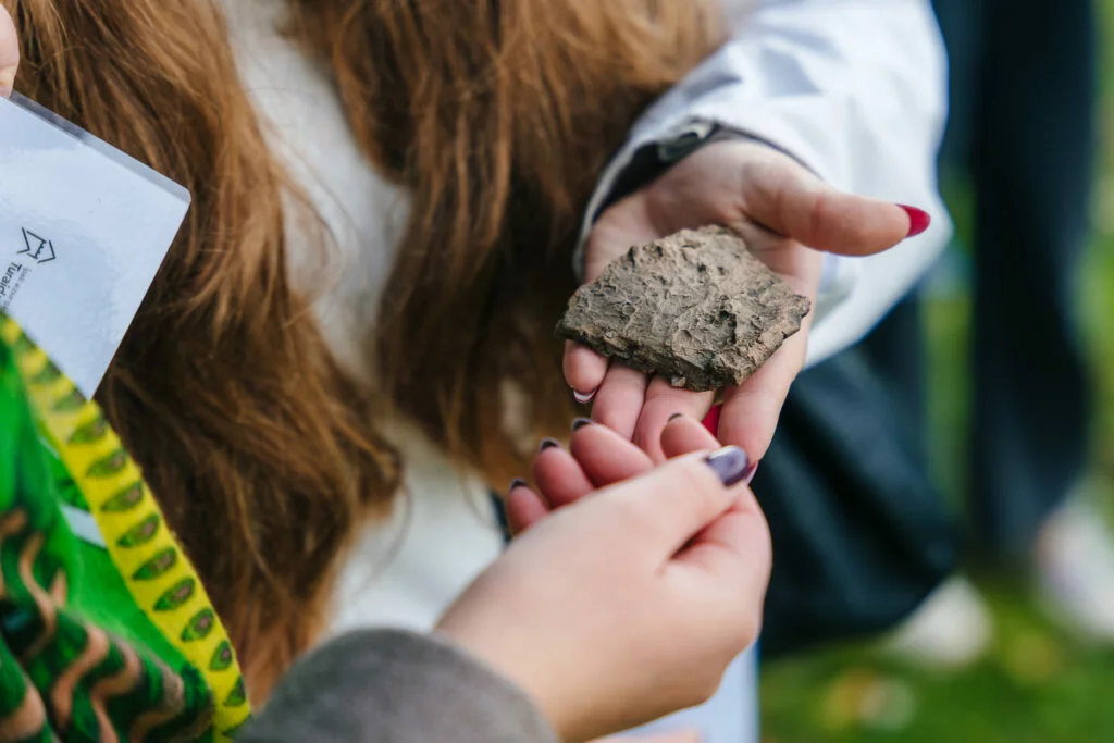 Dainu kalns – vieta līdzdalībai. Skolniece tur plaukstā akmeni.