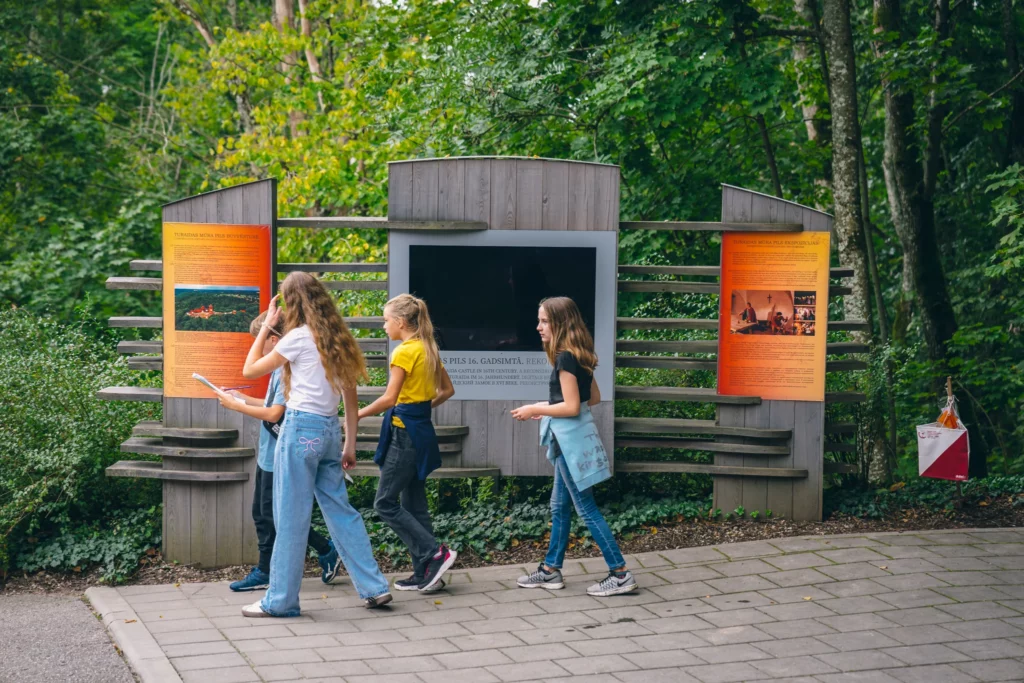 Muzejpedagoģiskās programmas Orientēšanās spēle Tūkstošgades stāsts Skolnieces apskata muzejrezervāta informatīvos stendus