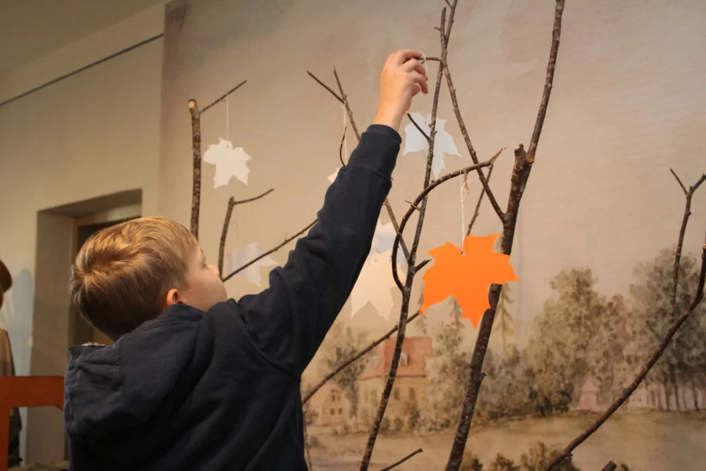 Muzejpedagoģiskās programma Uzvārdu došana Vidzemē Skolnieks iekar zaros oranžu papīra kļavas lapu