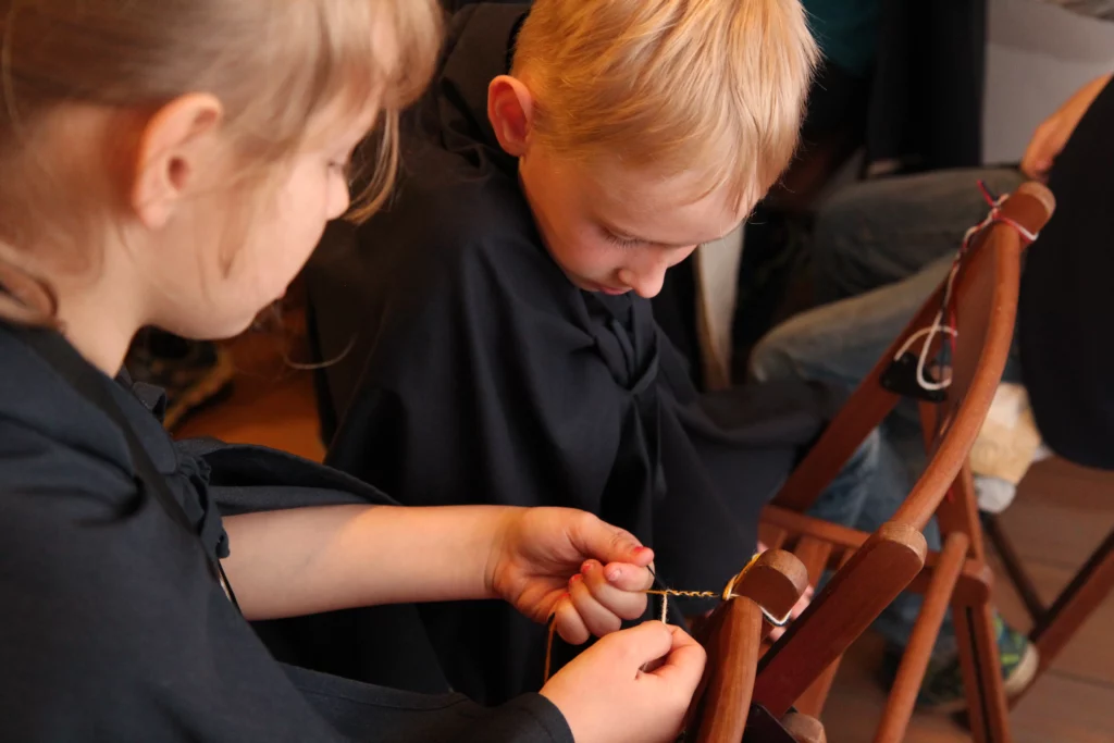 Muzejpedagoģiskā programma Ko lems līvu likteņzirgs? Grupas skolnieki mezglo pīnītes.