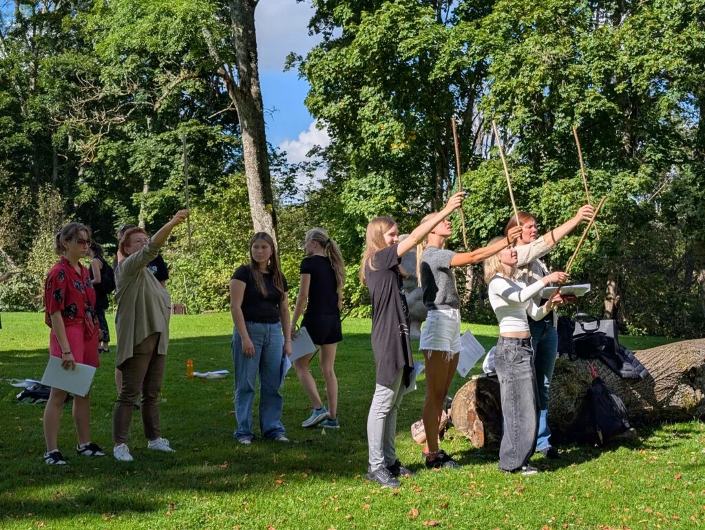 Koksnes krājas salīdzināšana kokiem Turaidas muzejrezervāta meža parkā (10.–12. kl.). Jaunieši pēta koku zarus.