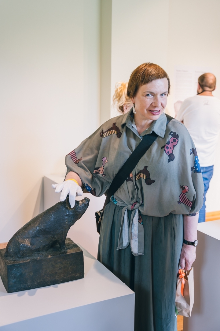 izstāde “Astainie līdzgaitnieki. Teodora Zaļkalna animālijas”. Sieviete pie cūciņas skulptūras.