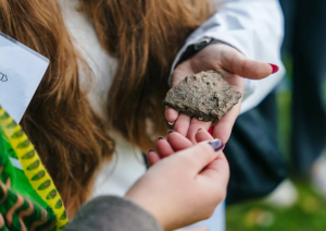 Dainu kalns – vieta līdzdalībai. Skolniece tur plaukstā akmeni.
