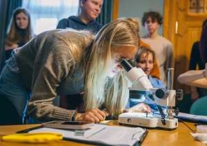 uraidas muzejrezervāta meža parka ūdenstilpnēs sastopamo bezmugurkaulnieku daudzveidības salīdzināšana un izmantošana ūdenstilpnes ūdens kvalitātes noteikšanai 10.–12. klašu skolēniem. Jauniete ar mikroskopa palīdzību pēta ūdens paraugu.